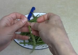 Using a needle and thread, insert the thread into the green beans, then tie the knot